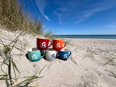Bunte Kaffeebecher stehen am Strand in einer Düne