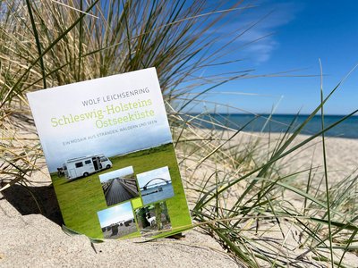 Ein Buch liegt am Strand in einer Düne