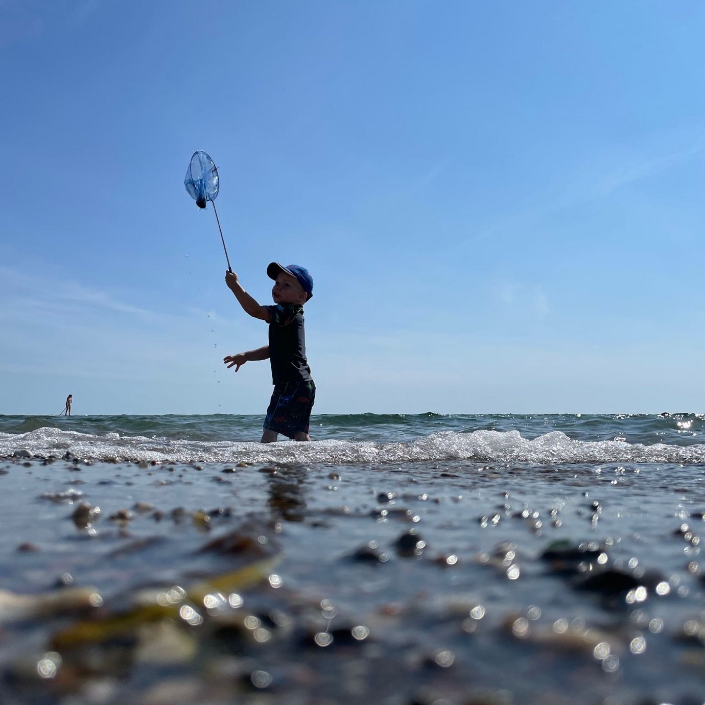 Ein Junge spielt am Strand mit einem Kescher