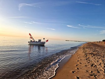 Ein Boot liegt bei Sonnenuntergang vor dem Strand