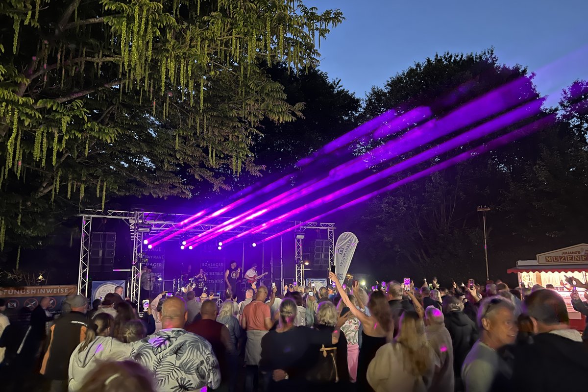 Menschenmenge vor Bühne mit Musikband und lilafarbenen Spotlights im Kurpark