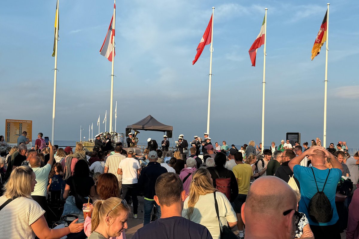 Eine Menschenmenge am Meer, im Hintergrund spielt eine Blaskapelle