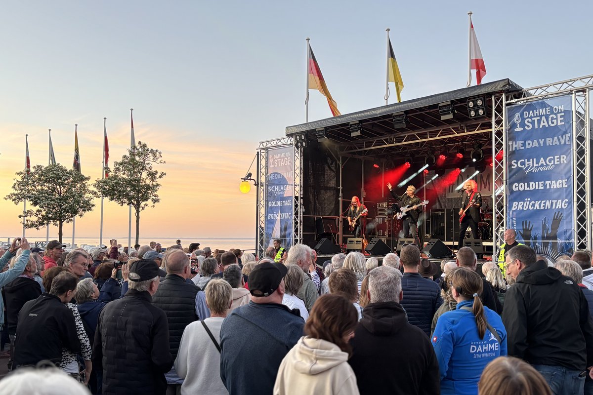 Menschenmenge vor Bühne mit Musikband während des Sonnenuntergangs