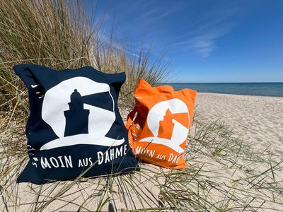 Zwei Stoffbeutel liegen am Strand in einer Düne