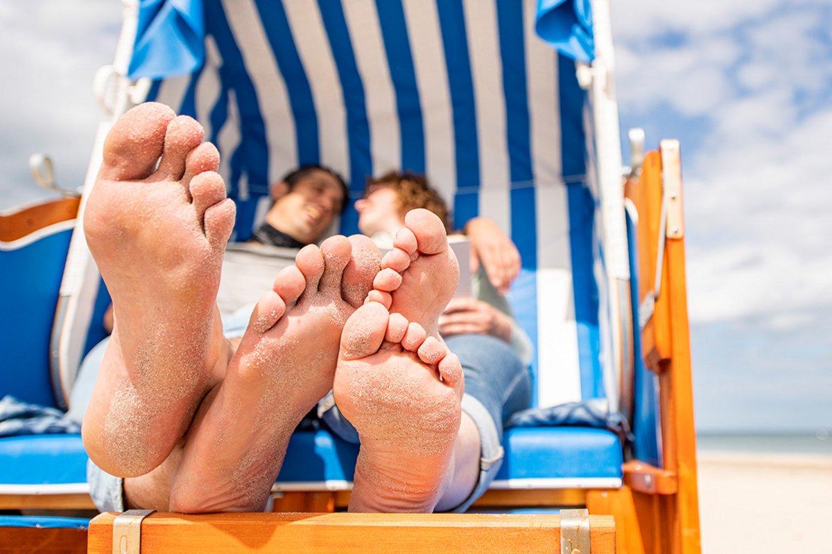 Sandige Füße eines Paares, das in einem Strandkorb liegt