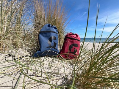 Zwei Sportbeutel stehen am Strand in einer Düne