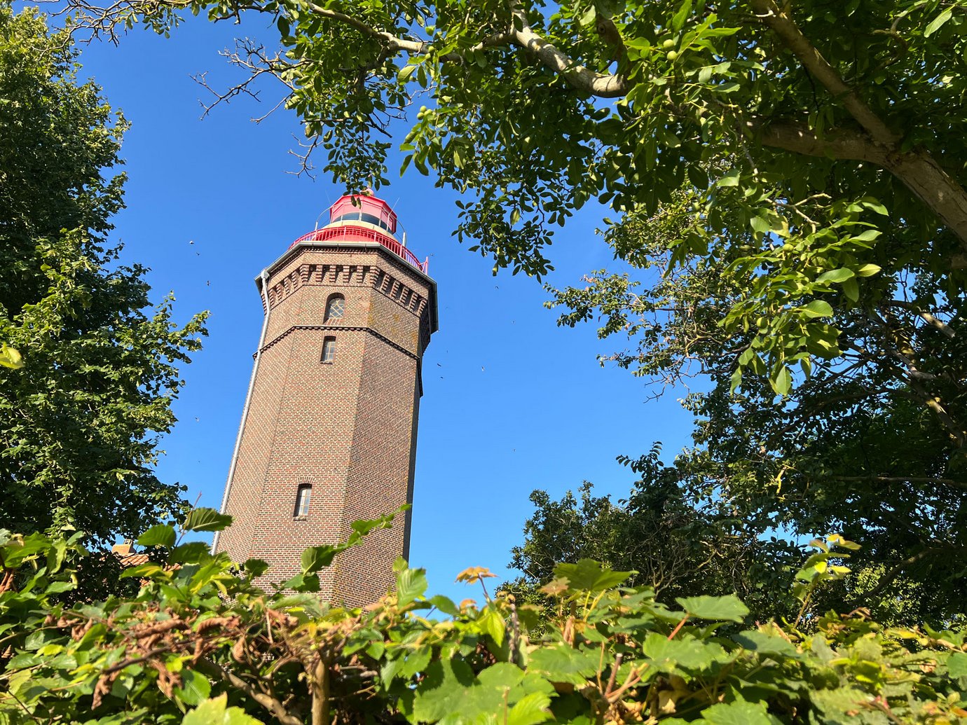Ein Leuchtturm aus Backsteinen mit einer roten Spitze
