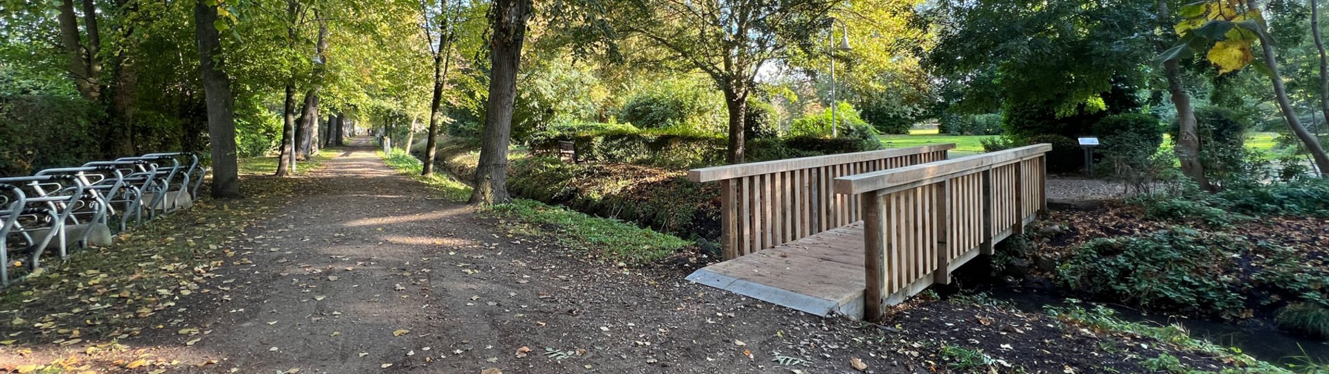 Eine Holzbrücke führt über einen kleinen Kanal in den Kurpark Dahme