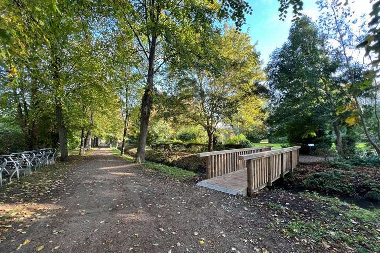 Eine Holzbrücke führt über einen kleinen Kanal in den Kurpark Dahme