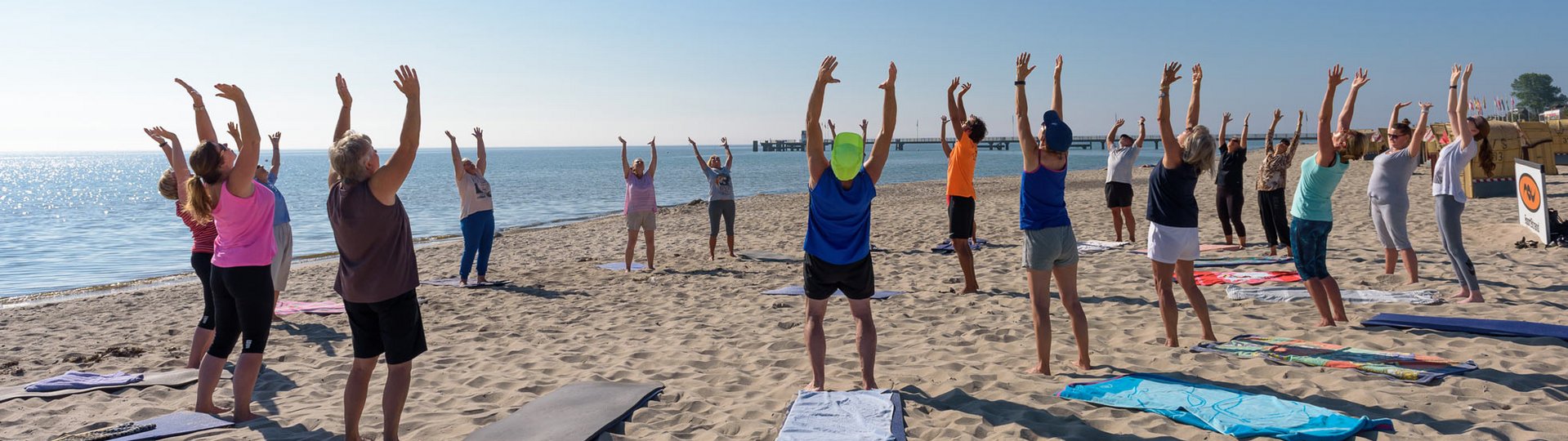 Eine Gruppe von Menschen in Sportkleidung macht Gymnastik am Strand