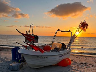 Ein Holzboot liegt bei Sonnenuntergang am Sandstrand