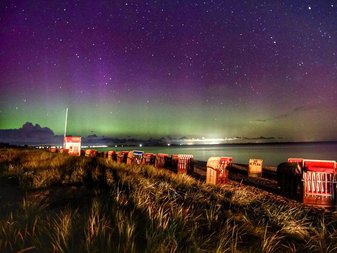 Der Dahmer Strand bei Nacht, am Horizont sieht man Aurora Borealis (Polarlichter) in Grün und Violett